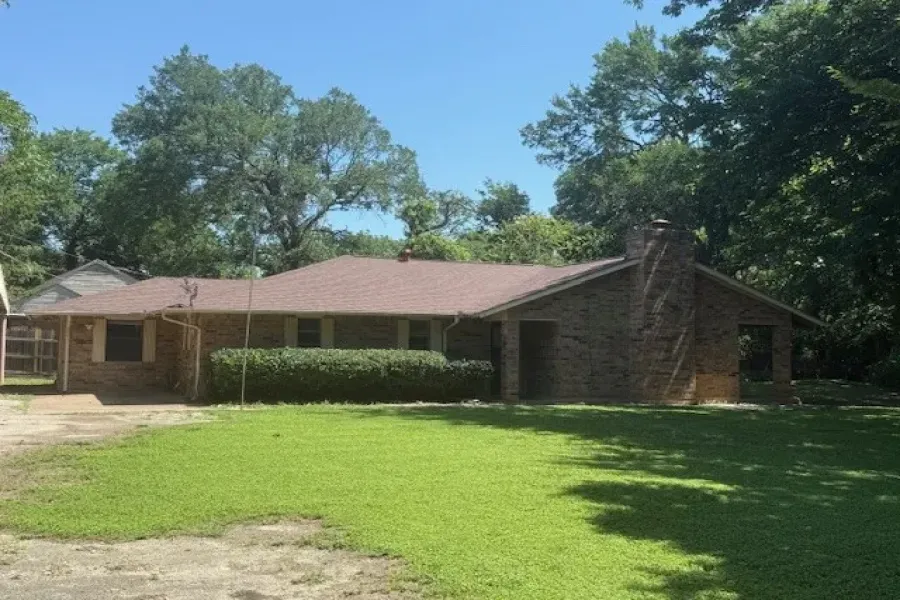 Ranch-style home with a front yard, a chimney, and brick siding
