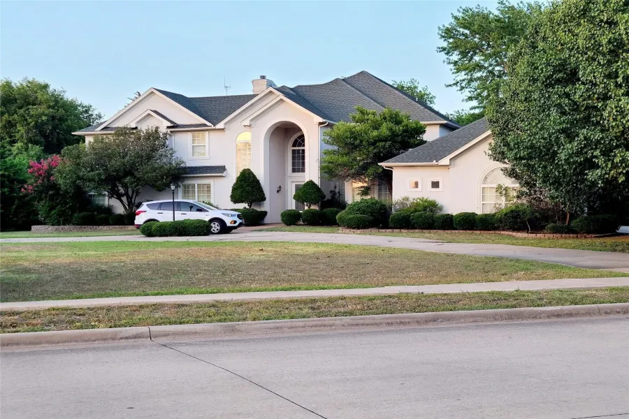 View of front of property with stucco siding, a front yard, and a chimney