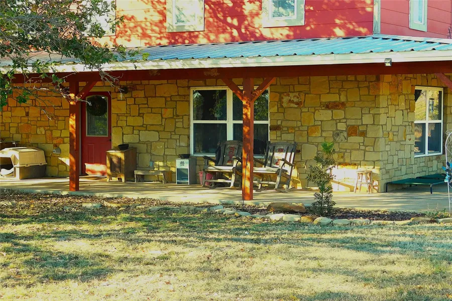 Property entrance with stone siding, a metal roof, and a lawn