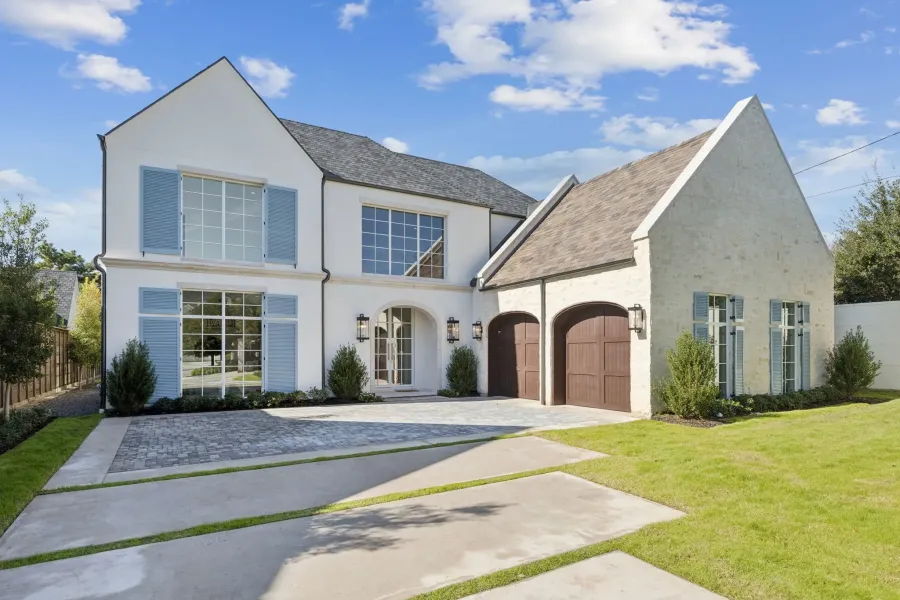 View of front facade with decorative driveway, a garage, stucco siding, and a high end roof