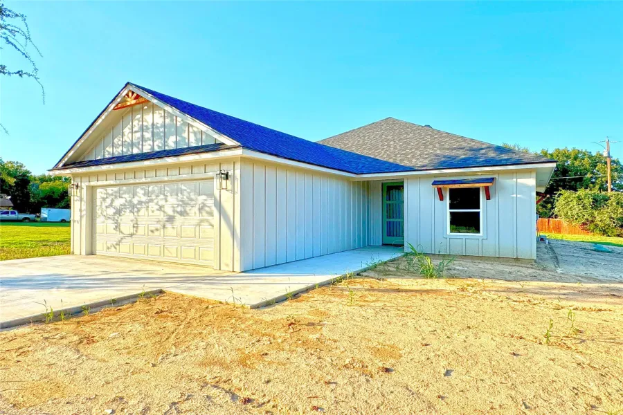 Ranch-style house with a shingled roof, a garage, board and batten siding, and concrete driveway