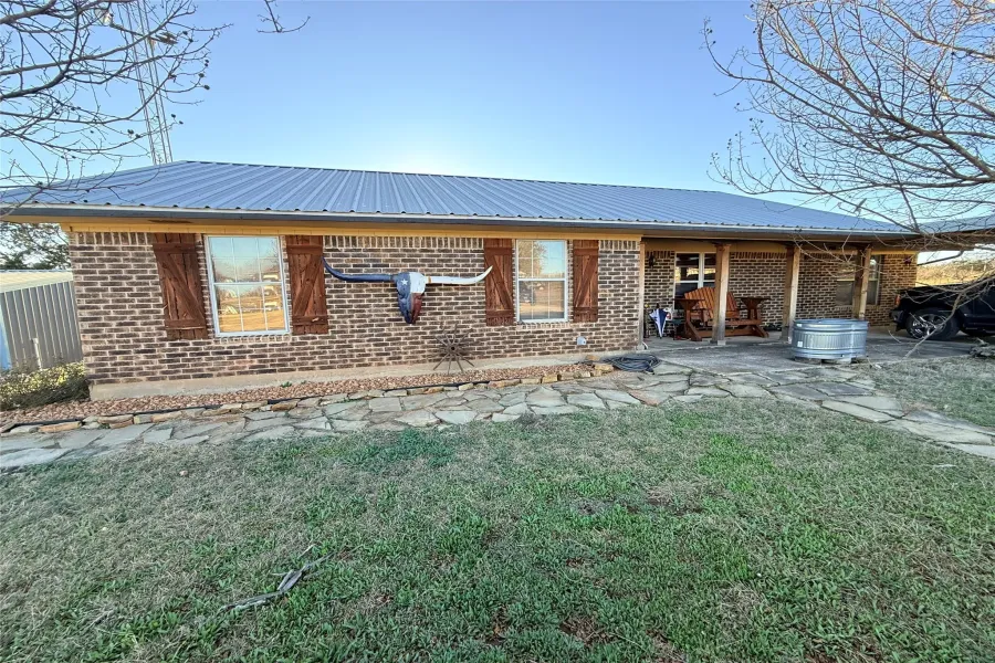 Rear view of property with a metal roof, brick siding, and a yard