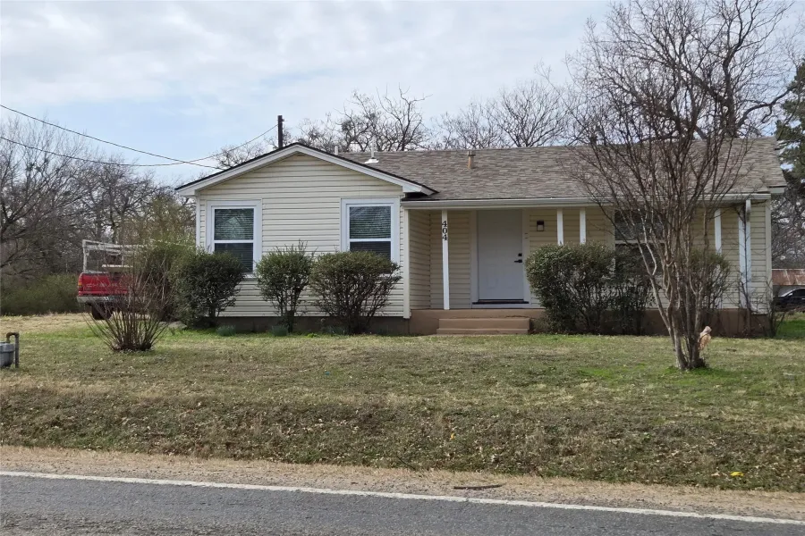 View of front of home with a front lawn, covered porch, and a shingled roof