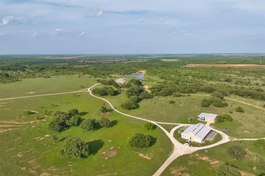 Expansive rural property featuring multiple structures, a private pond, and winding unpaved roads
