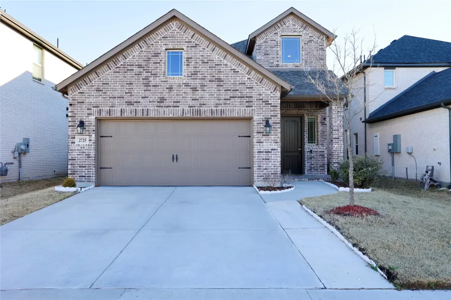 View of front of property featuring brick siding, driveway, and a garage