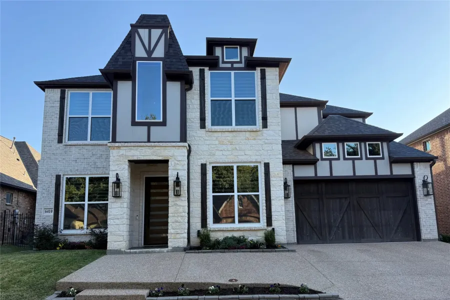 View of front of home with concrete driveway, a garage, stone siding, and roof with shingles