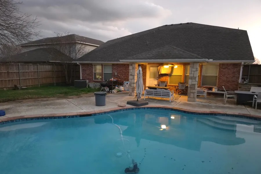 The property features a private swimming pool with integrated steps, a brick exterior, and a covered patio area with stone pillars