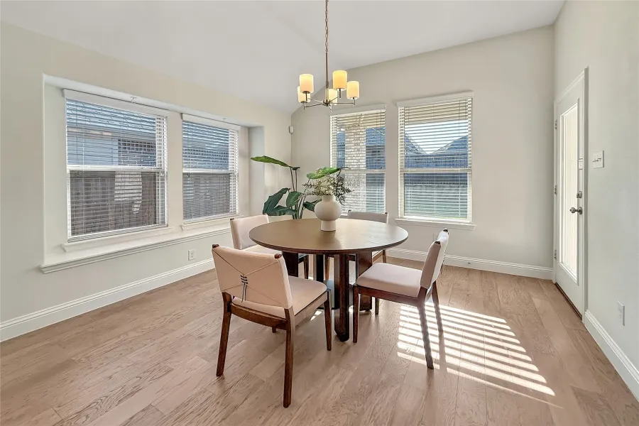 Kitchen featuring tasteful backsplash, a breakfast bar, stainless steel appliances, light stone countertops, and light wood finished floors