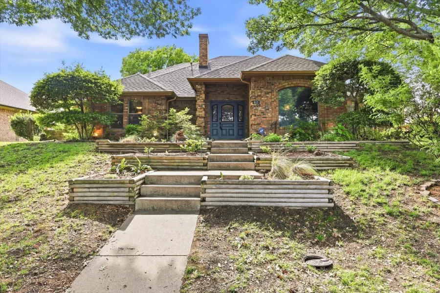 Brick exterior with a prominent arched window, a paneled front door, and a stone chimney
