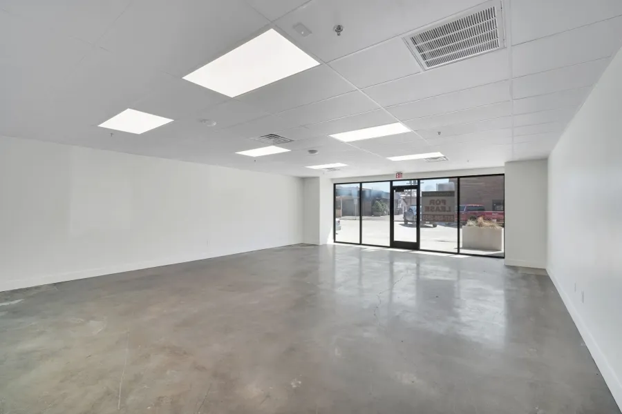 Expansive commercial space featuring a polished concrete floor, white walls, and a drop ceiling with recessed lighting