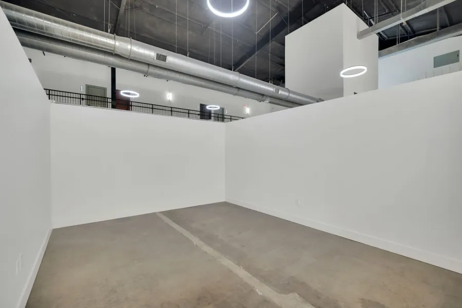 Expansive open-concept space featuring concrete flooring, crisp white walls, and industrial-style exposed ductwork