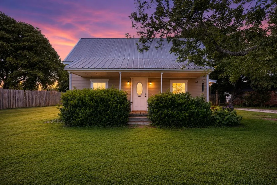 Front elevation featuring a metal roof, covered porch, and light-toned siding