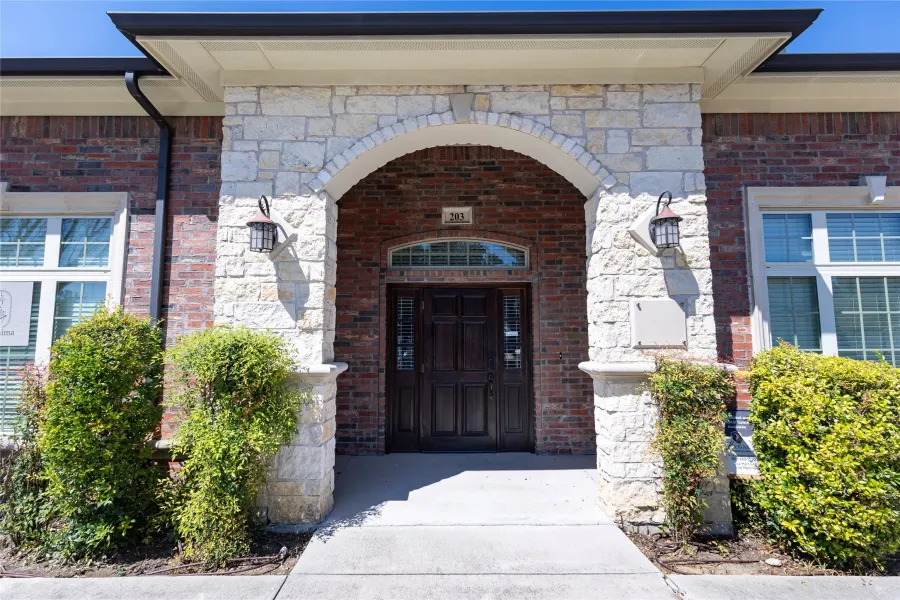 Entrance to property with stone siding and brick siding