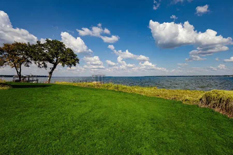 Expansive waterfront lawn featuring mature trees and direct access to the water