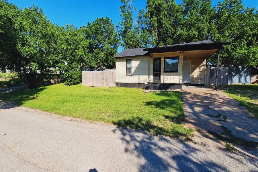 Single-story residence featuring a carport, front porch, and a fenced yard