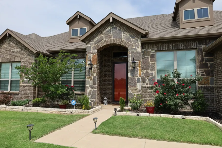 Brick and stone facade featuring an arched entryway with a red door
