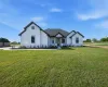 Modern farmhouse featuring board and batten siding and a front lawn