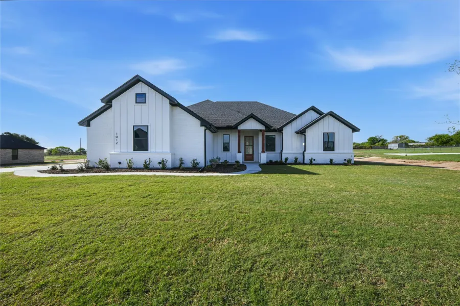 Modern farmhouse featuring board and batten siding and a front lawn