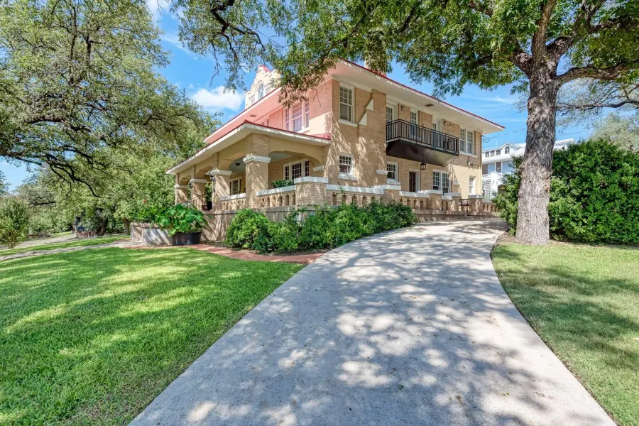 View of front of home with a balcony, a front lawn, a chimney, and a porch