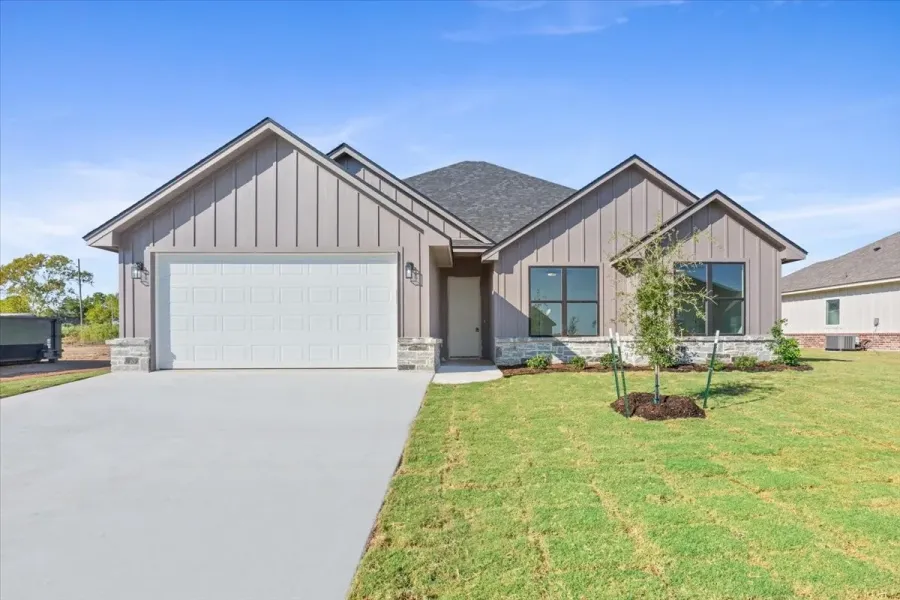 View of front of home featuring board and batten siding, an attached garage, concrete driveway, and a front lawn