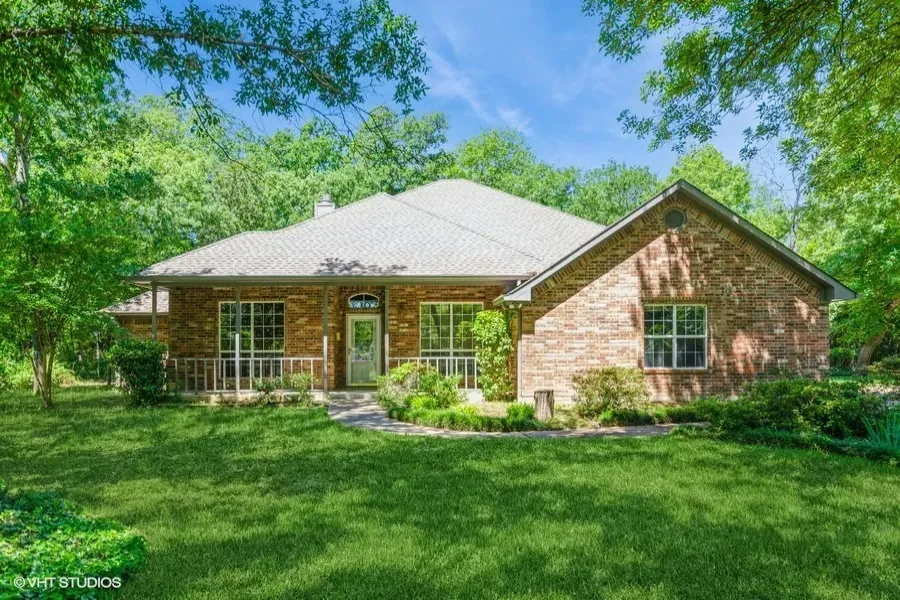 Single story home featuring brick siding, a front yard, a chimney, and a porch
