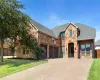 View of front of property featuring stone siding, roof with shingles, a garage, driveway, and a front lawn