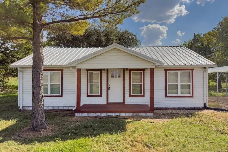 View of front facade featuring a porch, a metal roof, and a front lawn