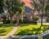 View of front of property with a yard, roof with shingles, brick siding, a garage, and concrete driveway