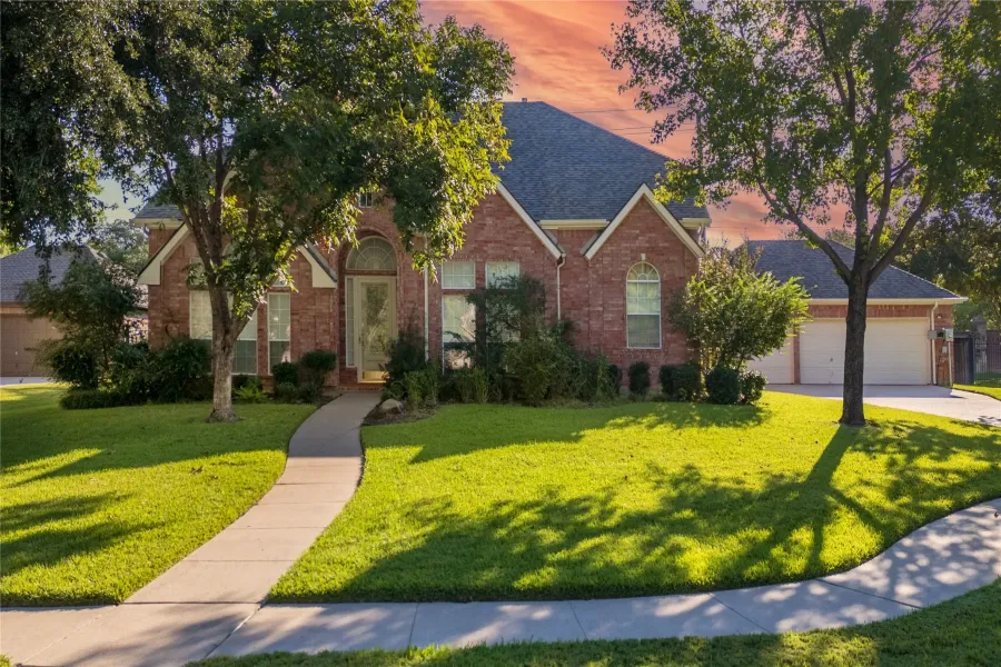 View of front of property with a yard, roof with shingles, brick siding, a garage, and concrete driveway