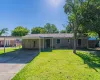 Single story home featuring a front yard, brick siding, concrete driveway, and a carport