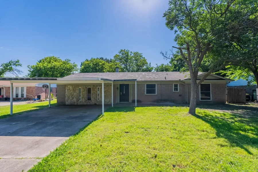 Single story home featuring a front yard, brick siding, concrete driveway, and a carport