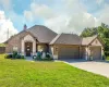 French country inspired facade featuring brick siding, a front lawn, an attached garage, and roof with shingles