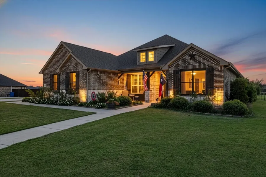 View of front facade with a front lawn, brick siding, and stone siding