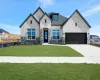View of front facade with a front lawn, stone siding, brick siding, concrete driveway, and an attached garage