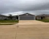 View of front facade featuring a front lawn, driveway, and an attached garage