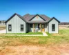 Modern farmhouse with roof with shingles, a front yard, a porch, and board and batten siding