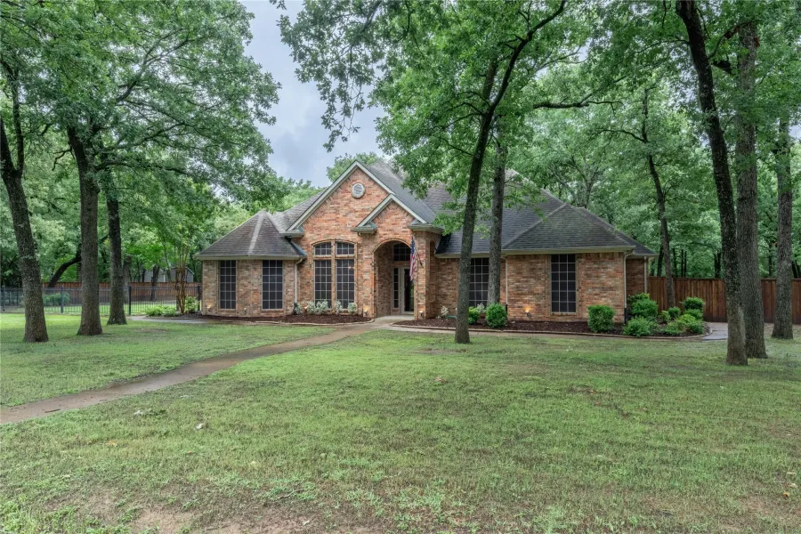 View of front of property featuring brick siding and roof with shingles