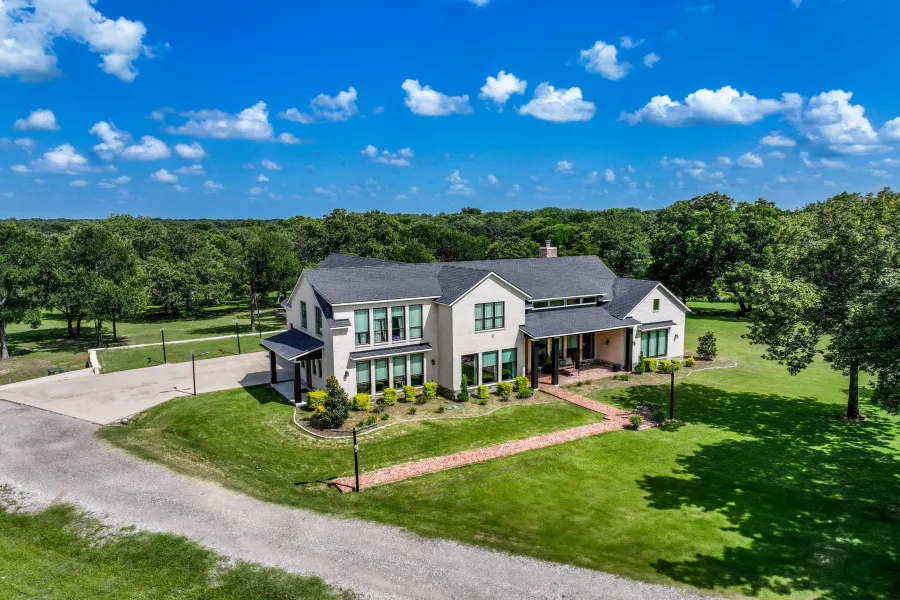 Private gated front elevation of the custom brick home with manicured landscaping and drive.