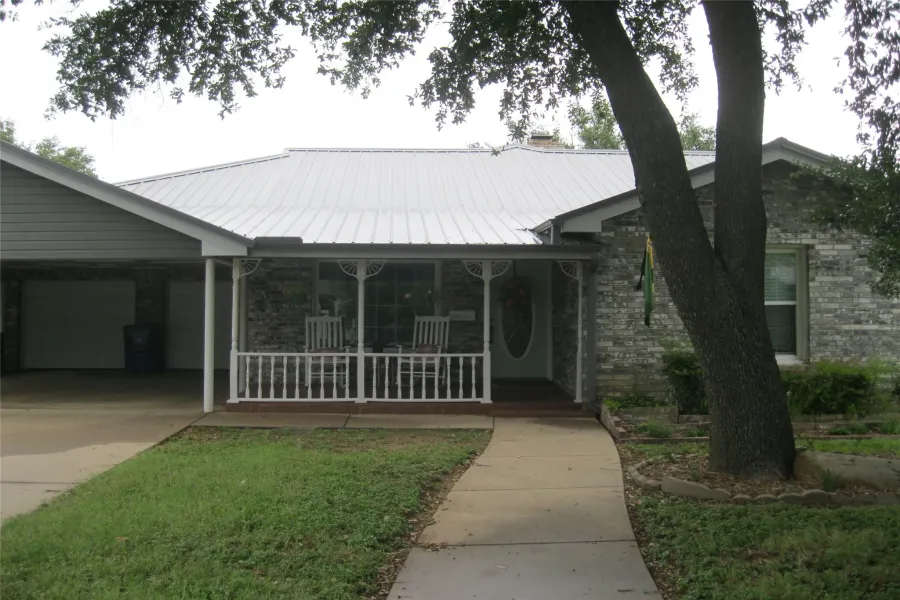 Ranch-style home featuring covered porch, concrete driveway, a metal roof, and an attached garage