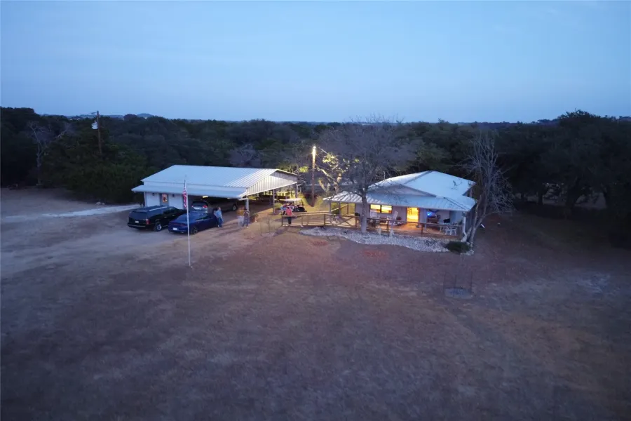 The property features a primary structure with a covered porch and an additional structure providing covered parking, both with white roofs