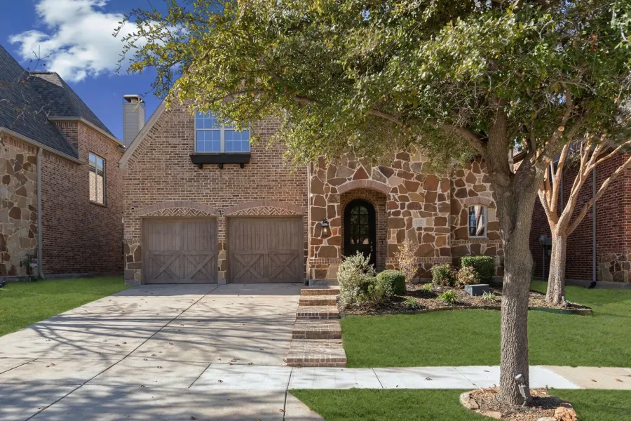 View of front of home featuring stone siding, a front yard, brick siding, driveway, and an attached garage