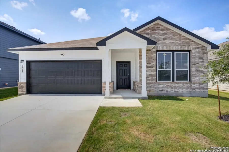 View of front facade featuring brick siding, an attached garage, driveway, and a front lawn