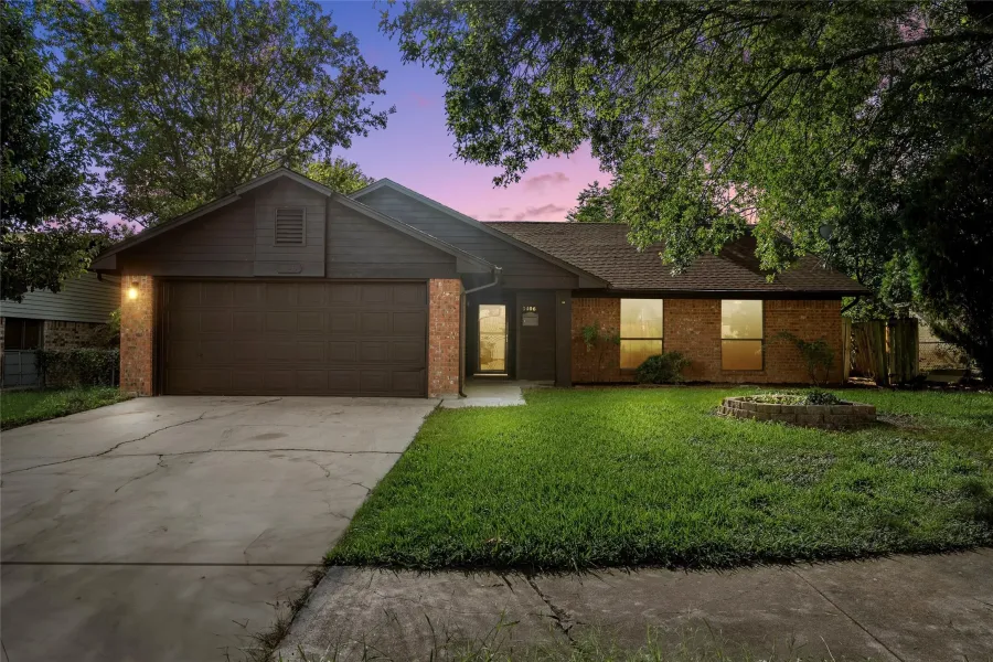 Ranch-style home featuring brick siding, a garage, concrete driveway, and a front lawn