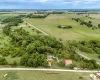Aerial view of the property, featuring expansive green fields, mature trees, and a road