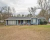 Single story home featuring covered porch, a front lawn, and a shingled roof