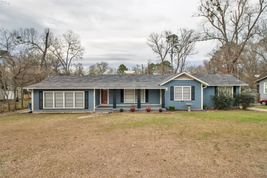 Single story home featuring covered porch, a front lawn, and a shingled roof