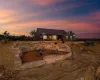 Back of house at dusk with a fire pit, a patio area, and solar panels