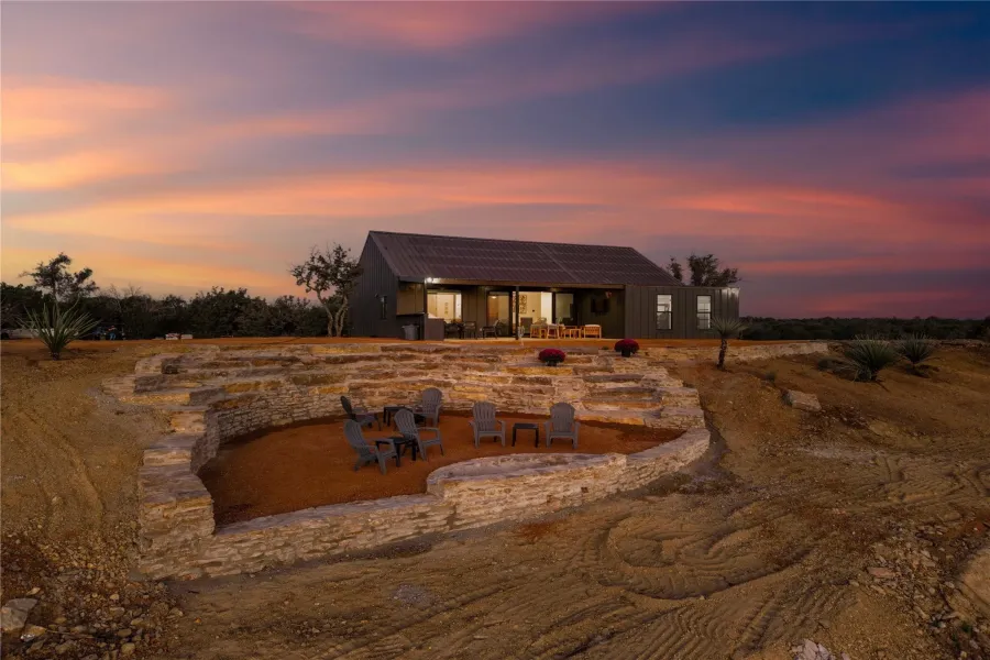Back of house at dusk with a fire pit, a patio area, and solar panels