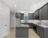 Kitchen with light stone counters, gray cabinets, a center island, appliances with stainless steel finishes, and backsplash