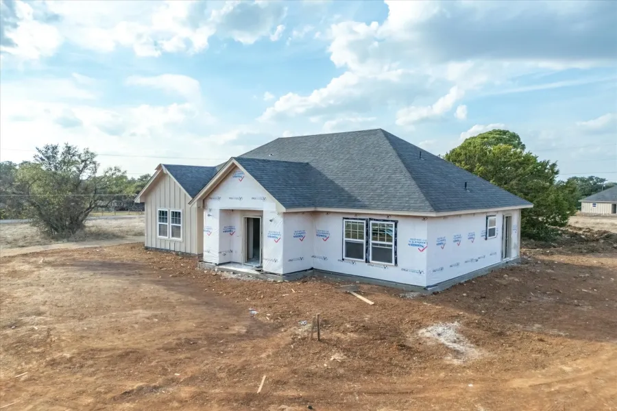 Property in mid-construction featuring roof with shingles